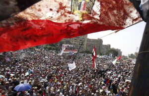 An Egyptian flag stained with blood flutters over members of the Muslim Brotherhood and supporters of deposed Egyptian President Mursi during a protest outside Raba El-Adwyia mosque in Cairo