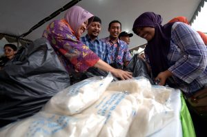 Walikota Surabaya, Tri Rismaharini (kiri) melayani pembeli berupa kemasan satu kilogram gula pasir ketika berlangsungnya operasi pasar murah di kawasan pasar sentra ikan Bulak, Kenjeran, Surabaya, Jatim, Kamis (11/7).