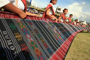 Sejumlah pelajar memegang kain ulos sepanjang 426 Meter yang ditenun secara manual selama bulan saat pembukaan acara Festival Danau Toba di Balige, Toba Samosir, Sumut, Rabu (17/9).
