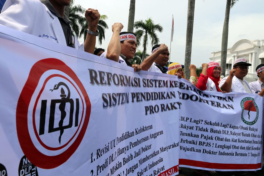 Sejumlah dokter yang tergabung dalam Ikatan Dokter Indonesia (IDI) Sumut membentangkan poster saat berunjuk rasa di halaman Kantor Gubernur Sumatra Utara, di Medan, Sumut, Senin (24/10). Mereka menolak program Dokter Layanan Primer (DLP) karena dinilai memberatkan dan memboroskan anggaran. ANTARA FOTO/Irsan Mulyadi/kye/16